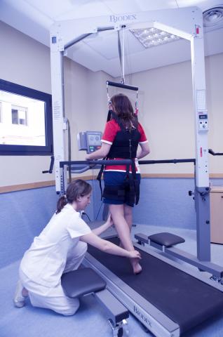 image Personal sanitario ayudando a una persona que hace ejercicios de rehabilitación en una cinta andadora en un hospital de Madrid