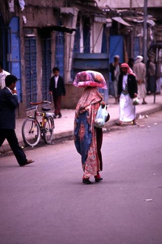 image Mujer con bulto sobre la cabeza en una calle de Sanaa, Yemen