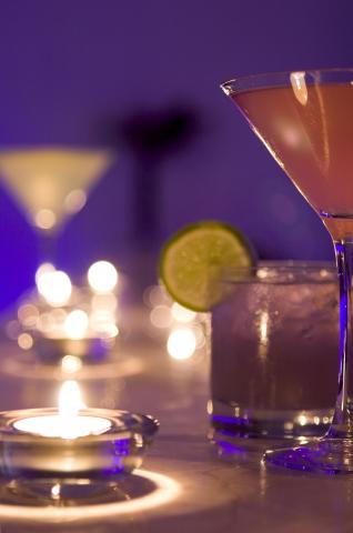 image Velas que adornan la barra de un bar junto a una copa y un vaso de bebida