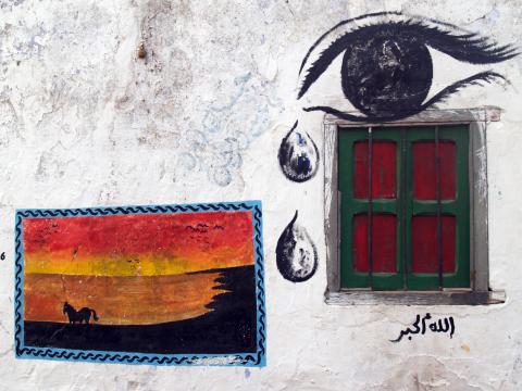 image Pintura de un ojo llorando y cuadro con caballo en una calle de Assilah, Marruecos